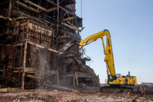 Excavator with shears tearing down building