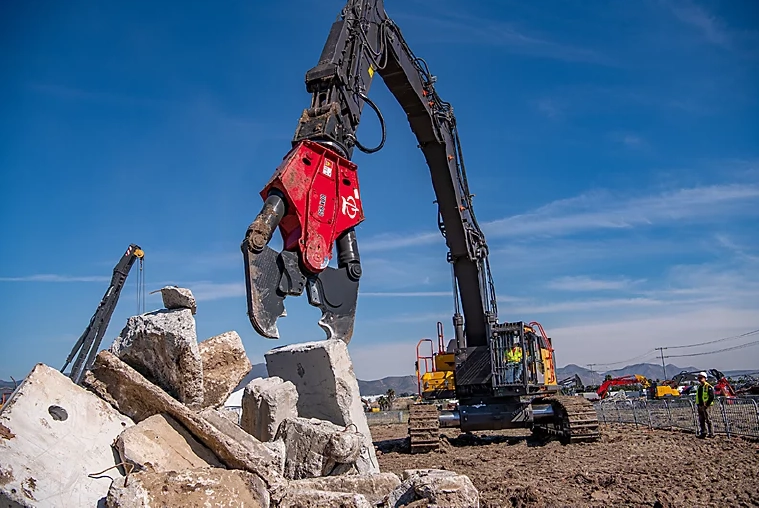 LaBounty demolition shear attachment mounted on an excavator crushing large concrete slabs at an active construction and demolition site.
